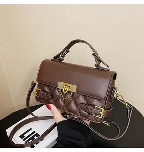 Detail der dunkelbraunen Stepptasche mit goldenem Drehverschluss und festem Handgriff