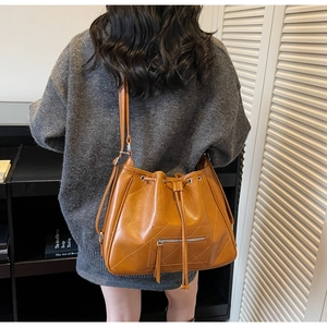 Détail d'un sac cabas marron en cuir matelassé avec cordon de serrage et fermeture éclair