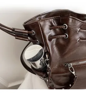 Detail view of the deep brown glossy bucket bag side pocket with a metal grommet