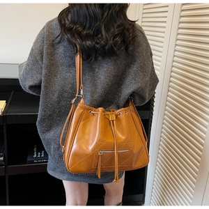 Detailed close-up of caramel quilted leather bucket bag featuring a drawstring closure