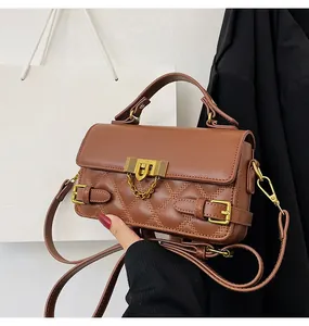 Nahaufnahme der braunen gesteppten Handtasche mit goldenem Schloss und Ketten-Detail