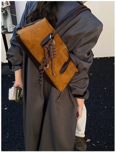 Detail of the brown suede shoulder bag with textured leather strap and hanging charms