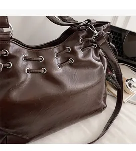 Close-up of dark brown tote bag featuring silver metal eyelets and leather drawstring details