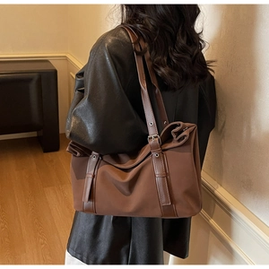 Detail of vintage large tote bag with brown leather strap and metal buckle on shoulder