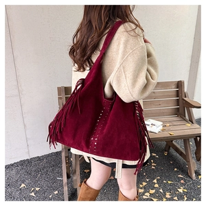 Dettaglio borsa tote in pelle scamosciata rossa con frange e borchie metalliche a stella