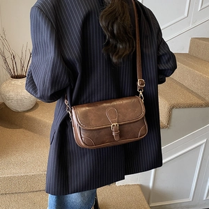 Retro deep brown PU leather crossbody bag with vintage buckle on navy striped blazer