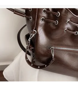 Detailed close-up of dark brown leather tote bag showing silver metal eyelets and stitching