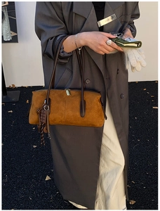 Brown suede shoulder bag with dual zippers and chocolate charm shown on model