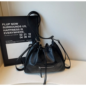 Détail du sac seau noir matelassé avec cordon de serrage et finitions métalliques argent