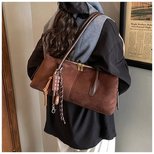 Detailed view of brown matte suede shoulder bag featuring gold zippers and charms