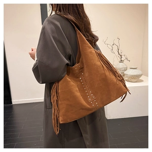 Borsa tote in camoscio marrone con frange laterali e borchie a stella metalliche su una modella