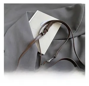 Detail of adjustable brown leather strap and dual silver zippers on yellow suede bag