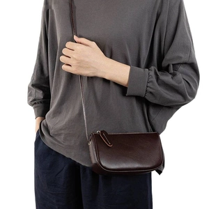 Brown leather crossbody bag with minimalist semi-circular design and adjustable strap