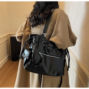 Close-up of black glossy leather tote bag with silver eyelets and drawstring details
