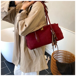 Detail of burgundy suede shoulder bag with thin leather strap and braided zipper pull