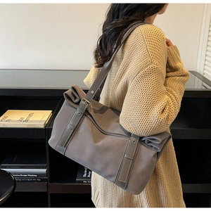 Detail of dark grey nylon shoulder bag with adjustable vertical decorative straps and buckles