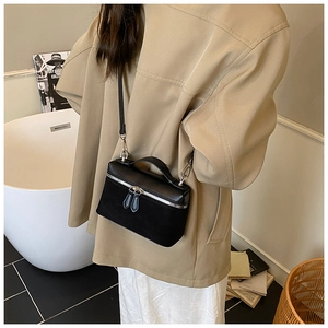 Detail of black rectangular leather crossbody bag with dual textures and metal zippers