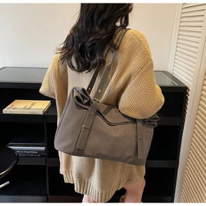 Detail of adjustable leather shoulder straps with metal eyelets on gray tote bag