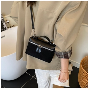 Side view of model wearing a black structured square crossbody bag with dual-texture leather
