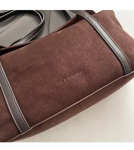 Detail of dark brown suede shoulder bag with embossed CLEAROK logo and leather trim