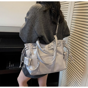 Macro detail of high-capacity pearl grey leather tote bag with side drawstring and studs