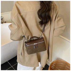 Detailed view of brown leather crossbody bag with dual-zipper and mixed texture finish