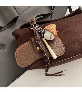 Detail of creative baseball charm with leather glove and wooden bat on suede bag