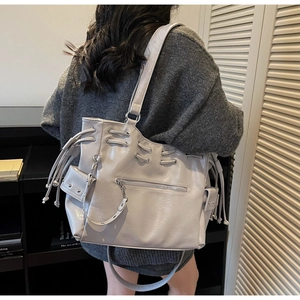 Detail view of a large silver tote bag featuring side drawstring and rivet decorations