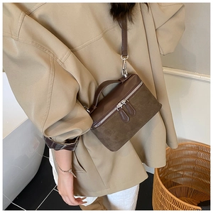 Close-up of a retro dark brown suede square crossbody bag with leather top handle