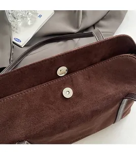 Detail of dark brown matte underarm bag showing magnetic closure and premium hardware