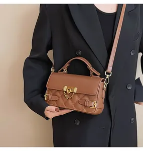 Detail der braunen gesteppten Ledertasche mit goldener U-Schnalle und Kette am Modell