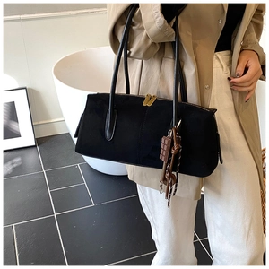 Close-up of black suede tote bag with golden zippers and chocolate-shaped charm