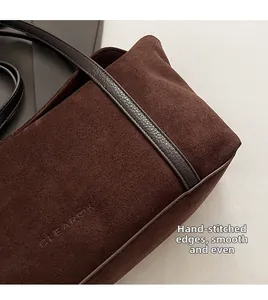 Close-up of deep brown suede handbag with CLEAR OK logo and fine hand-stitched detailing