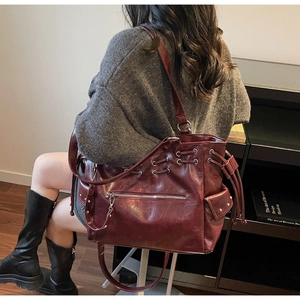 Close-up of deep wine red leather tote bag with silver zippers and rivet details