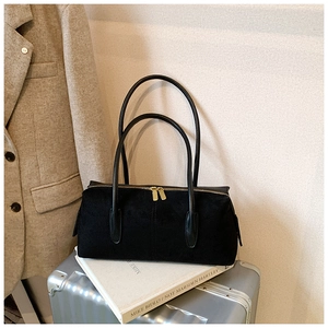 Detail of minimalist black suede shoulder bag with gold zippers and leather handles