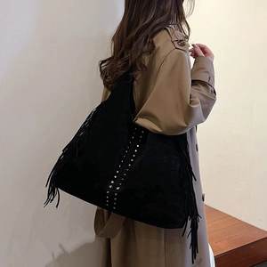 Borsa tote retrò nera opaca con frange e borchie a stella indossata da una modella con trench