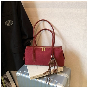 Detail of burgundy suede boston shoulder bag with golden zipper and decorative charms