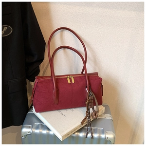 Detail of red matte Boston bag with metal zippers and unique nut pendant on silver trunk