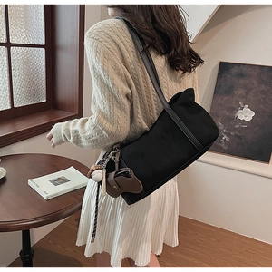 Detail of black matte shoulder bag featuring unique cat ear cutouts and baseball charm