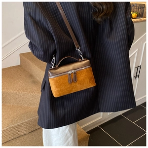 Detail of two-tone crossbody bag with brown metallic leather and yellow suede texture