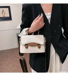Détail du sac bandoulière en cuir texturé avec une large sangle d'épaule décorative