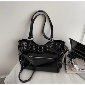 Detailed close-up of a black glossy tote bag with functional drawstring and metal zipper