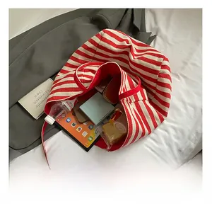 Detail showing the large interior capacity of the striped canvas tote bag with personal items