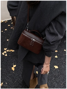 Detailed view of deep brown textured patchwork bag with dual silver zippers and handle