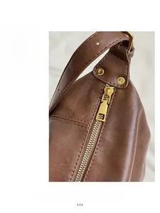 Détail de la fermeture éclair dorée et de la texture du cuir brun sur un sac cabas