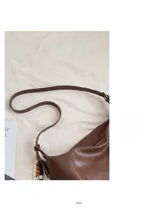Détail macro du sac cabas en cuir marron foncé avec charm vintage et boucle dorée
