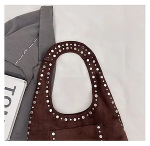 Détail du sac à bandoulière en daim marron avec rivets métalliques et design vintage