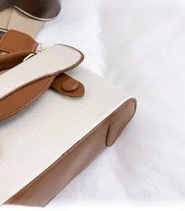 Gros plan sur la texture du cuir grainé et la boucle en métal du sac à bandoulière bicolore