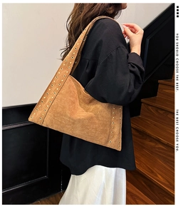 Detail shot of brown suede shoulder bag featuring gold eyelets and vintage biker aesthetic
