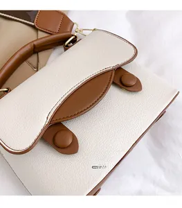 Détail du sac blanc et marron montrant la texture grainée et les boucles en métal